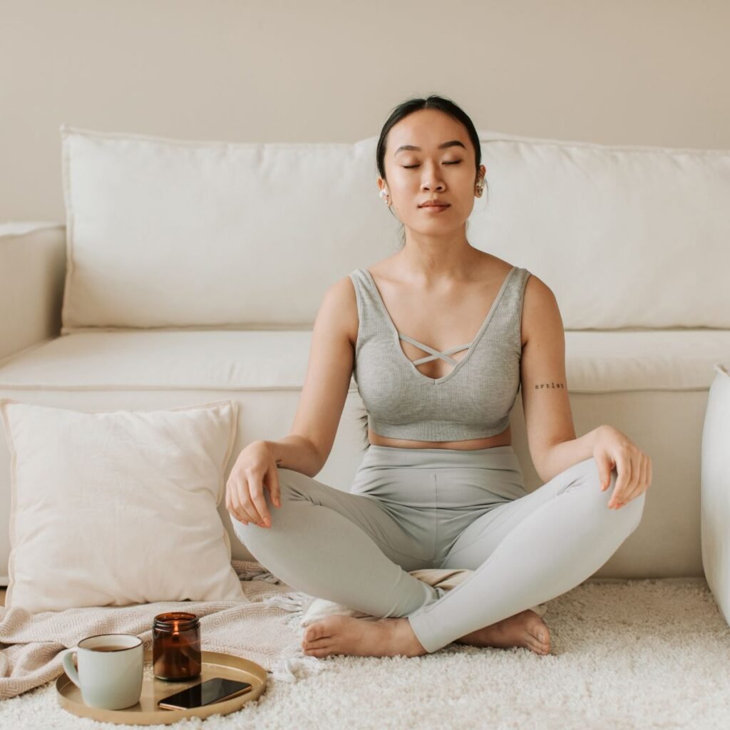 Como a meditação ajuda na saúde mental. A imagem mostra uma mulher sentada em posição de lotus e seu rosto expressa bem estar.