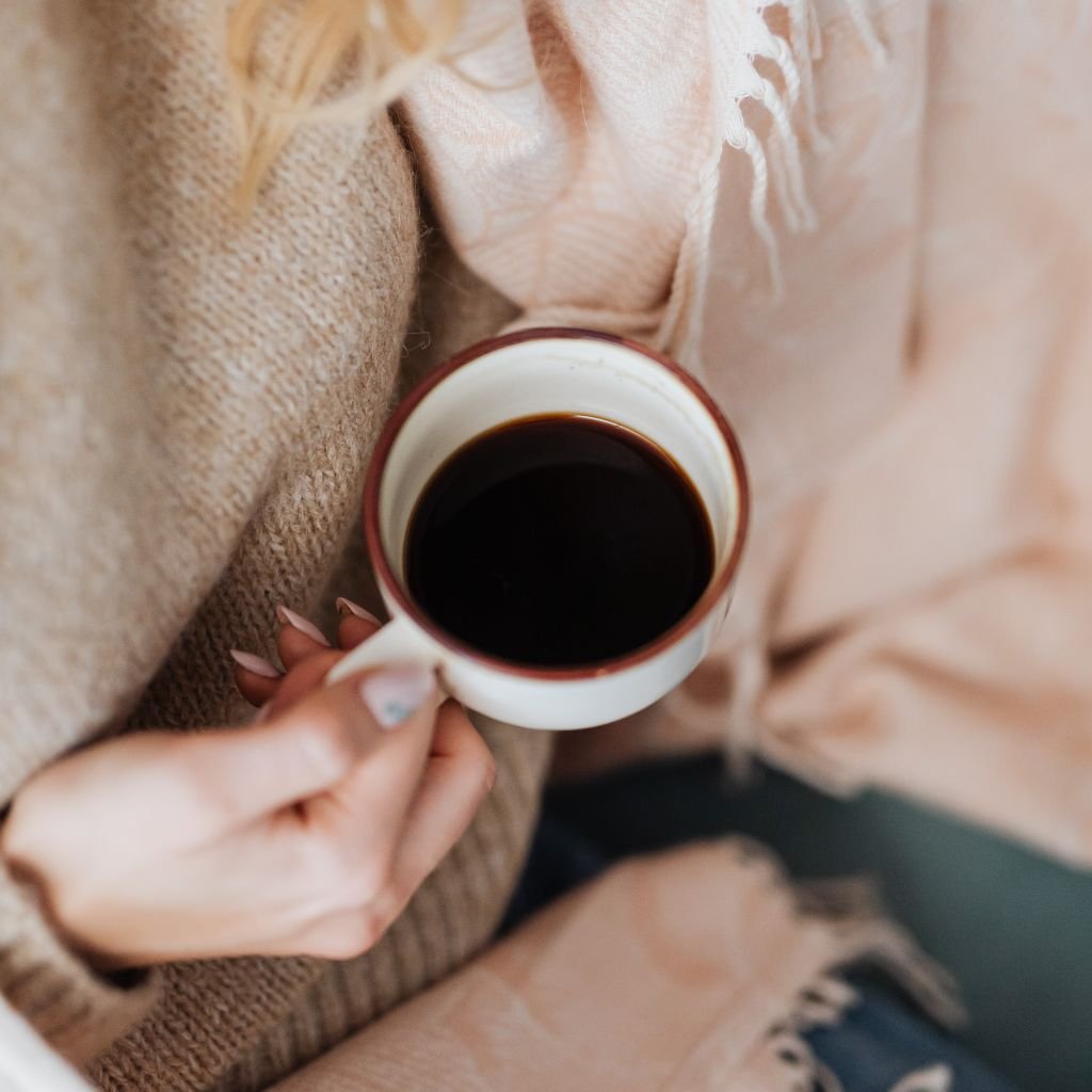 Uma pessoa segura uma xícara de café preto.