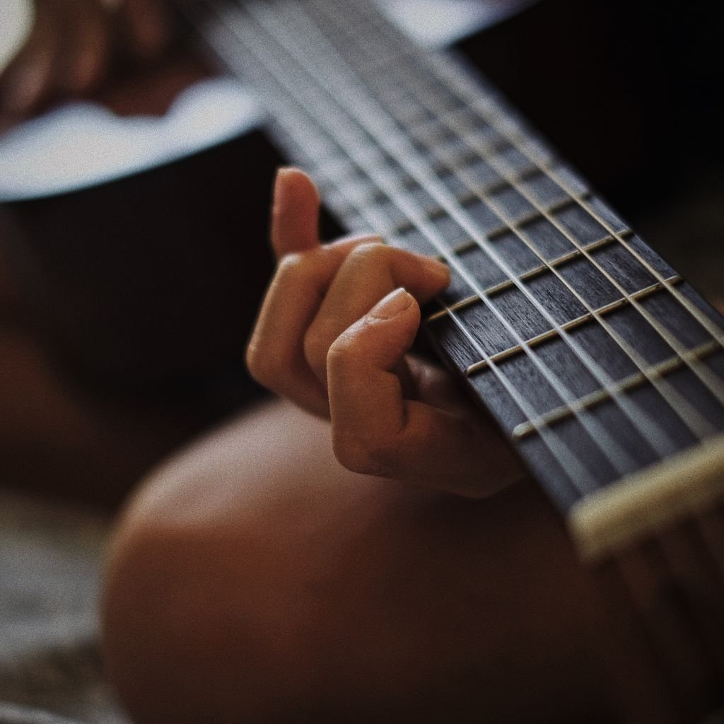 A imagem mostra uma pessoa tocando um violão sentada no chão, o que se relaciona com o assunto deste artigo, a produção da canção Chão de giz, pelo cantor e compositor Zé Ramalho.